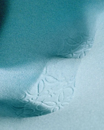 Close-up studio shot of a light-blue textured surface with a delicate floral pattern creating a soft, visually soothing effect.