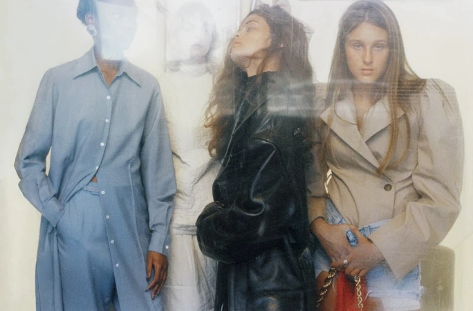 Fashion editorial featuring four women in stylish outfits; a blue shirt-pant set, a black leather jacket, and a beige blazer with denim shorts.