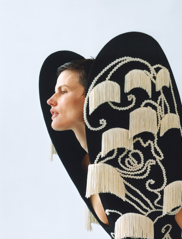 Woman in a black and white fringed dress posing in a studio. Close-up shot highlights the texture and design of the garment.
