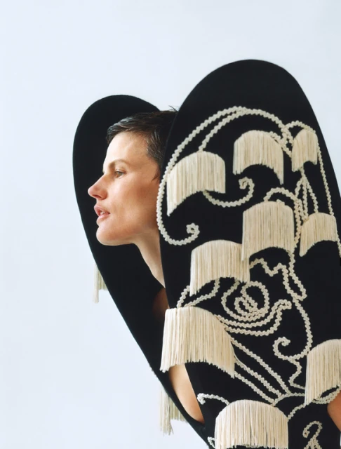 Woman in a black and white fringed dress posing in a studio. Close-up shot highlights the texture and design of the garment.