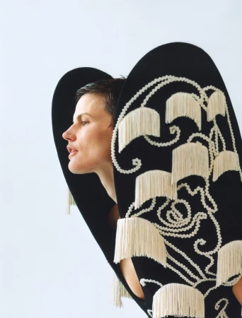 Woman in a black and white fringed dress posing in a studio. Close-up shot highlights the texture and design of the garment.