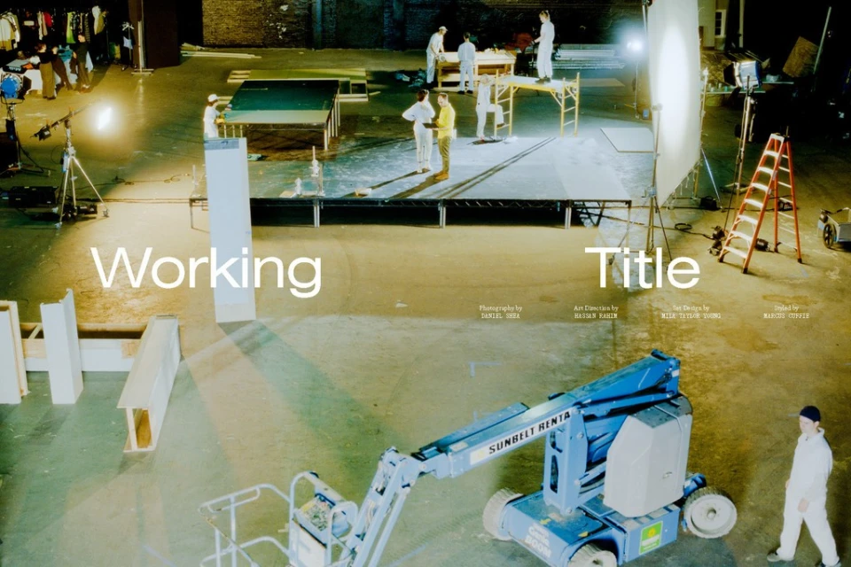 Film set with construction lift, film crew, ladder, and lighting equipment on a polished concrete floor, captured from a high-angle shot.