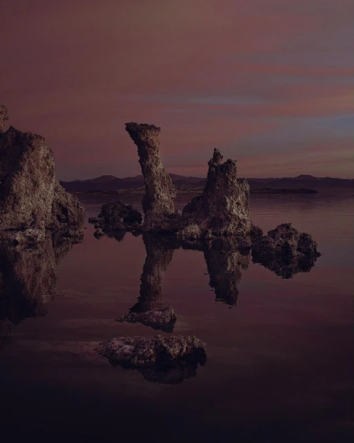 Scenic view of tufa rock formations in a lake at sunset, with their reflections visible in the calm water, creating a serene landscape.