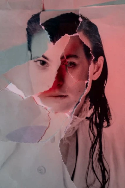 Close-up portrait of a woman with wet hair partially obscured by ripped paper, set against a red and turquoise color gradient background.