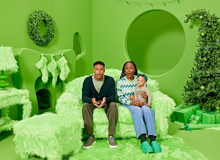 Family of three poses on a lime green furry couch in a matching room with a Christmas tree, decorations, and presents. 