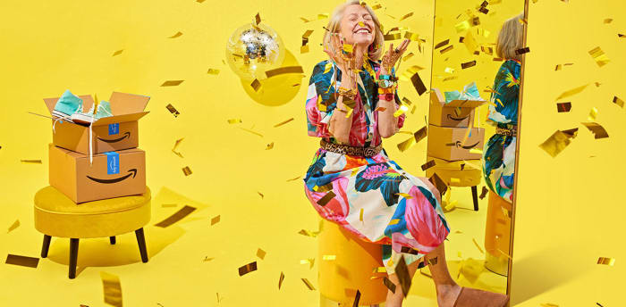 Blonde woman in floral dress celebrates online shopping with confetti, boxes, and a disco ball against a bright yellow background.