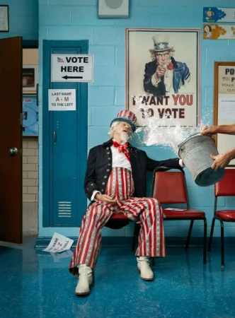 Man in Uncle Sam costume sits under 'Vote Here' sign as water is poured on his head from a bucket in political satire.