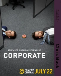 Two men lying flat on office carpet flooring with a frosted donut placed between them on the floor.