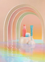Skincare products arranged on organic sculptural podiums beneath pastel arched frames with water reflection