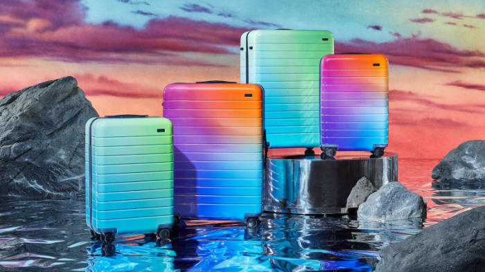Colorful suitcases stand in a row against a dramatic sky and rock formations for travel and tourism advertising.