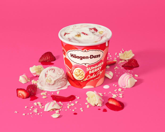 Haagen-Dazs Summer Berry Cake Pop ice cream in a container, with scoops, sliced strawberries, and cake pieces on a pink surface.