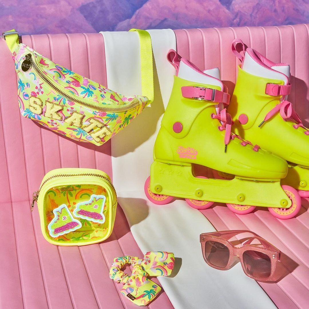 Still life of yellow roller skates, sunglasses, and accessories with a pink-and-white background, and tropical design accents.