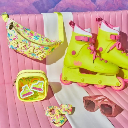 Still life of yellow roller skates, sunglasses, and accessories with a pink-and-white background, and tropical design accents.