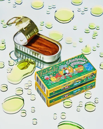 Still life of canned anchovies and oil droplets on a reflective surface, food photography with silver and green color scheme.