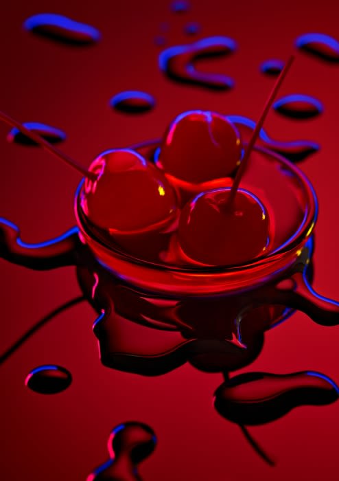Close-up of a glass filled with three cherries, presented on a red reflective surface with scattered water droplets and blue lighting.