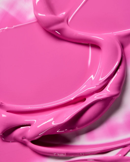 Close-up of vibrant pink paint with glossy texture, showcasing smooth strokes and creamy consistency against a bright background.