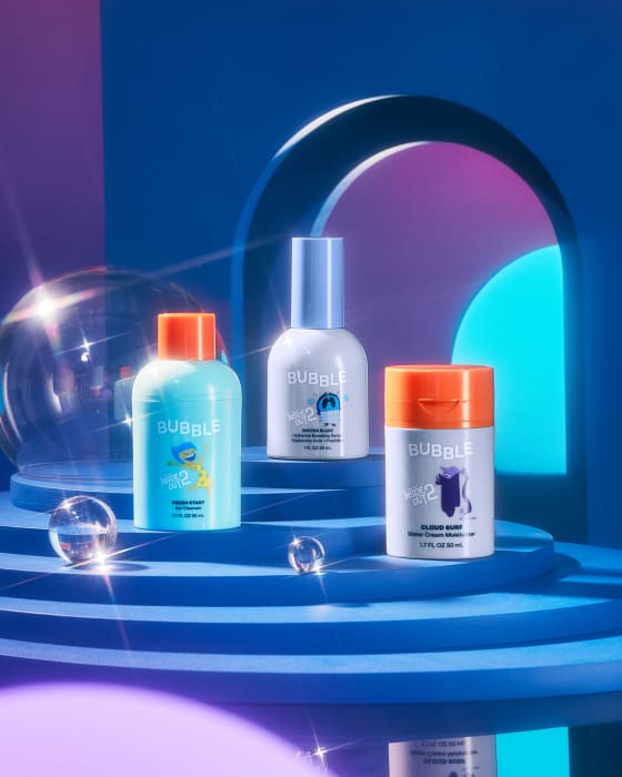 Three colorful Bubble skincare bottles displayed on a tiered surface against a blue gradient backdrop with a clear bubble orb.