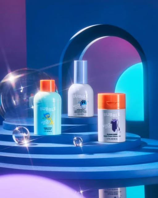 Three colorful Bubble skincare bottles displayed on a tiered surface against a blue gradient backdrop with a clear bubble orb.