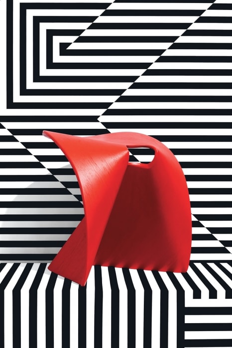 Abstract red chair in a geometric black and white stripe pattern setting. Modern furniture design in a visually dynamic presentation.