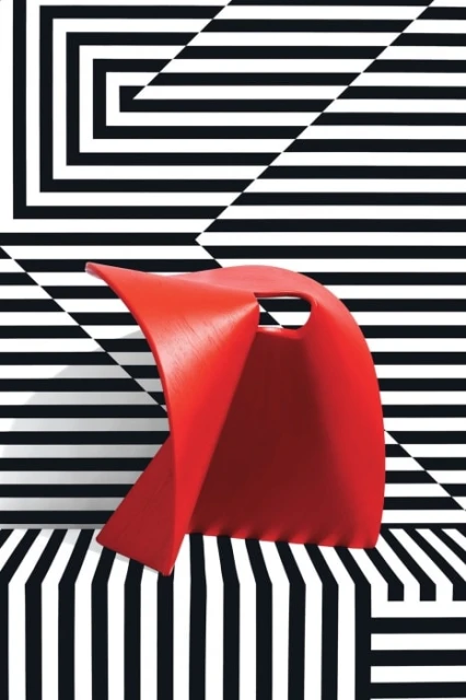 Abstract red chair in a geometric black and white stripe pattern setting. Modern furniture design in a visually dynamic presentation.
