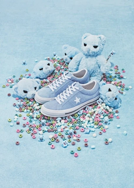 Light blue One Star Converse sneakers surrounded by a whimsical arrangement of teddy bears and pastel-colored donut-shaped cereal pieces.