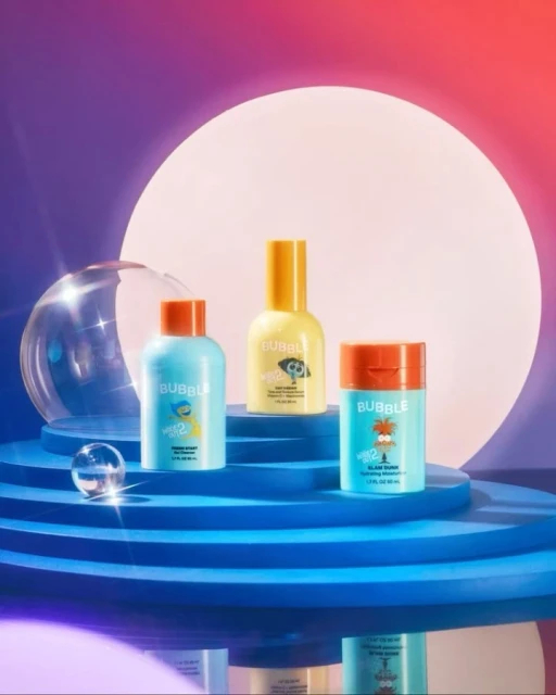 Three colorful Bubble skincare products on a tiered platform against a gradient background, showcasing beauty and skincare.