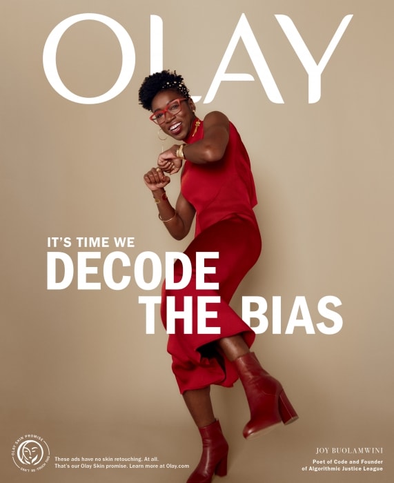 OLAY advertisement featuring a happy African-American woman in red dress and boots dancing in front of brand logo and mission statement.