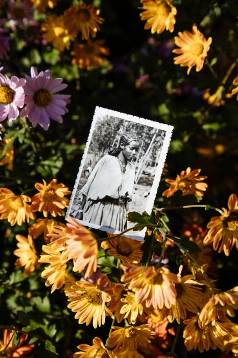 Monochrome portrait photo of a woman surrounded by vibrant orange and pink flowers, adding a layer of nostalgia and natural beauty.