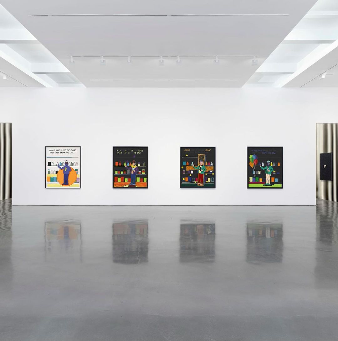 Art gallery exhibition featuring colorful paintings with figures and objects in a modern, brightly lit space with reflective flooring.