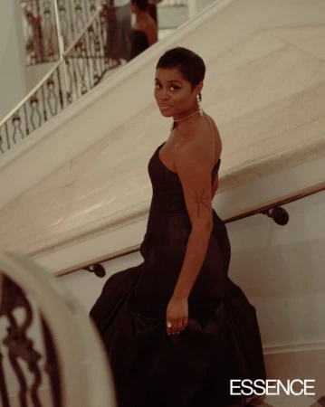 A Black woman with short hair wearing a strapless black evening gown on a grand staircase, photographed by Mahaneela.
