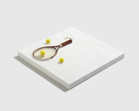 Vintage wooden tennis racket and three yellow tennis balls arranged on a raised white square platform against a white background.