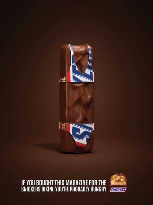 Snickers candy bar is depicted wearing a bikini with Snickers logo against a brown background in a promotional advertisement.