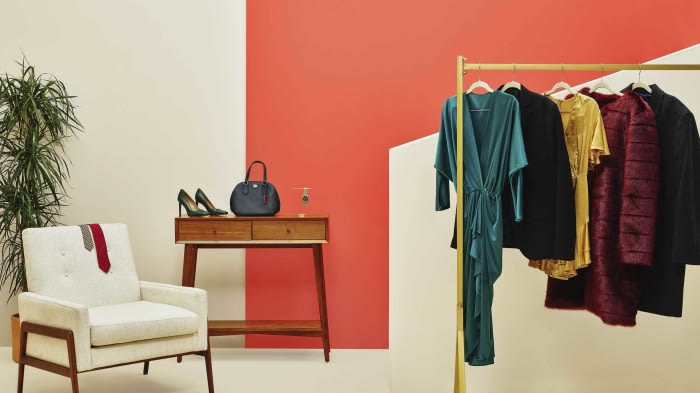 Interior view of stylish clothing rack, chair, table, and accessories, accented by color-blocked wall and potted plant creating an inviting display.