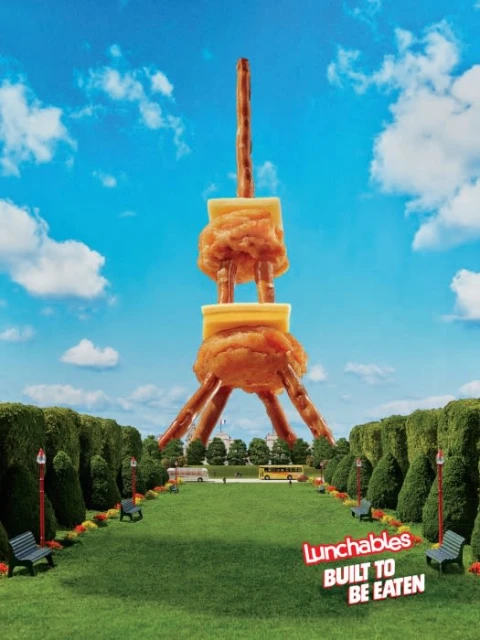 Eiffel Tower is assembled from Lunchables products against a bright blue sky. Food art and advertising for Lunchables brand.