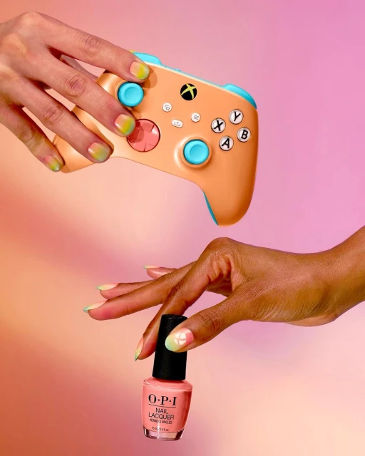 Gaming and beauty converge with nail art on an Xbox controller and nail polish, creating a vibrant blend of technology and fashion.