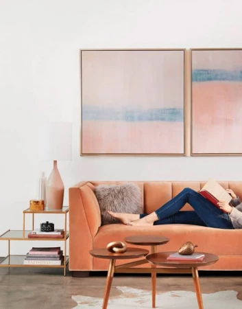 Woman reclining on a peach velvet sofa reading a book in a modern living room interior by Zen Sekizawa