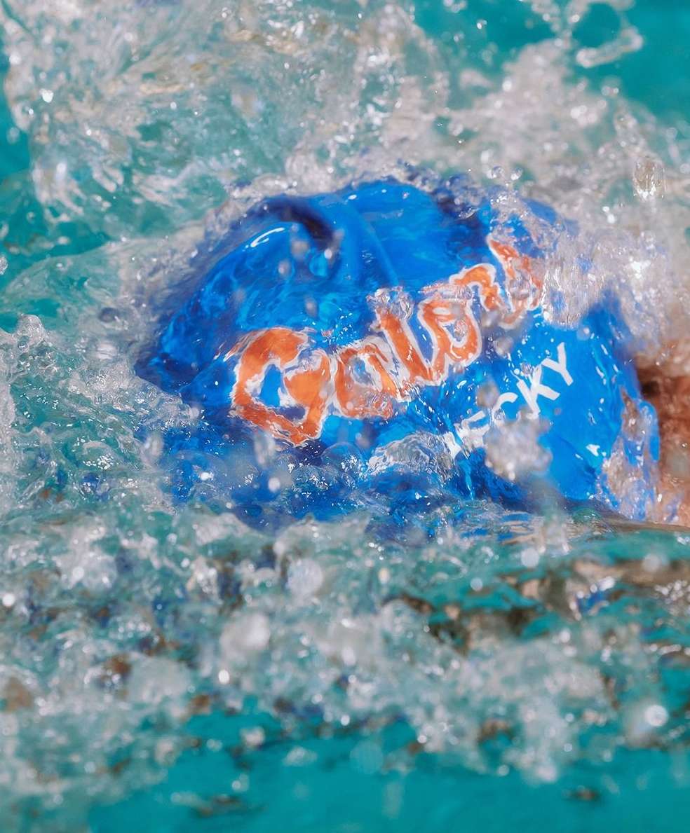 Close-up of a blue Galaxy chocolate wrapper submerged in water, with water droplets splashing around the brand name.