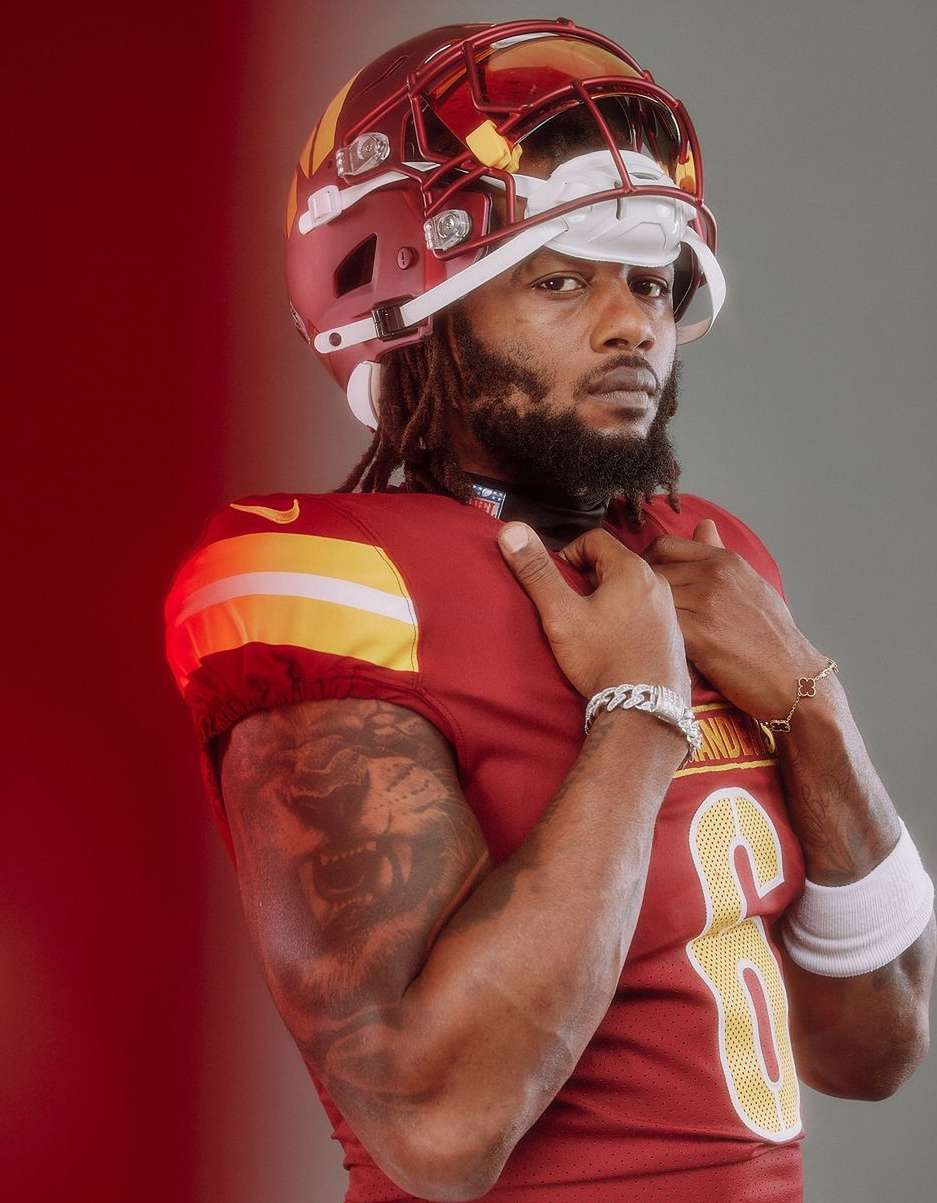Close-up portrait of a male American football player in burgundy uniform and helmet looking intensely at the camera.