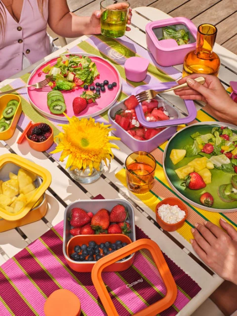 Overhead shot of a colorful tabletop picnic with fresh salads, fruits, and drinks, evoking a bright and inviting atmosphere.