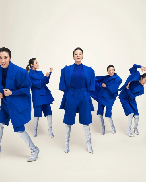 Multiple images of an adult woman wearing a blue jacket and short set with silver high heel boots against a neutral background.