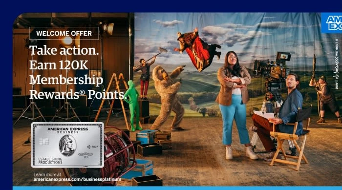 American Express business card ad with actors and crew on a film set. A woman and man are in foreground, with fantasy characters.