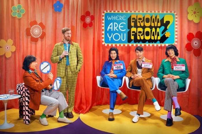 Retro-style game show scene features a diverse group of contestants and a host in colorful vintage clothing on a decorated stage.