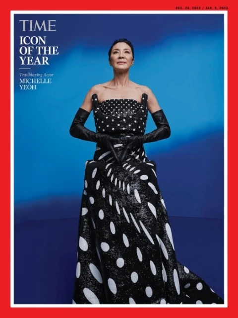 Michelle Yeoh, TIME's Icon of the Year, poses in a black and white polka dot gown and long gloves against a blue gradient background.