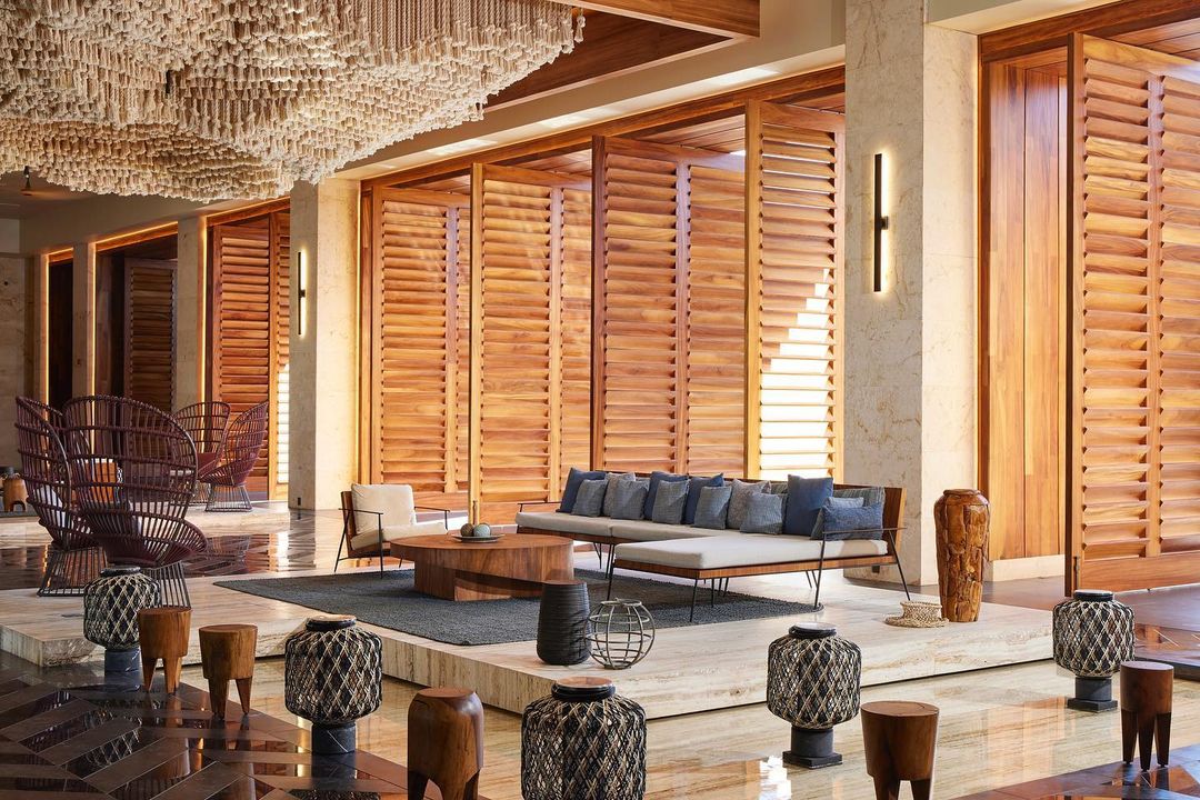 Lobby interior with wooden partitions, lounge seating, and decorative ceiling art, showcasing a modern design with natural materials.