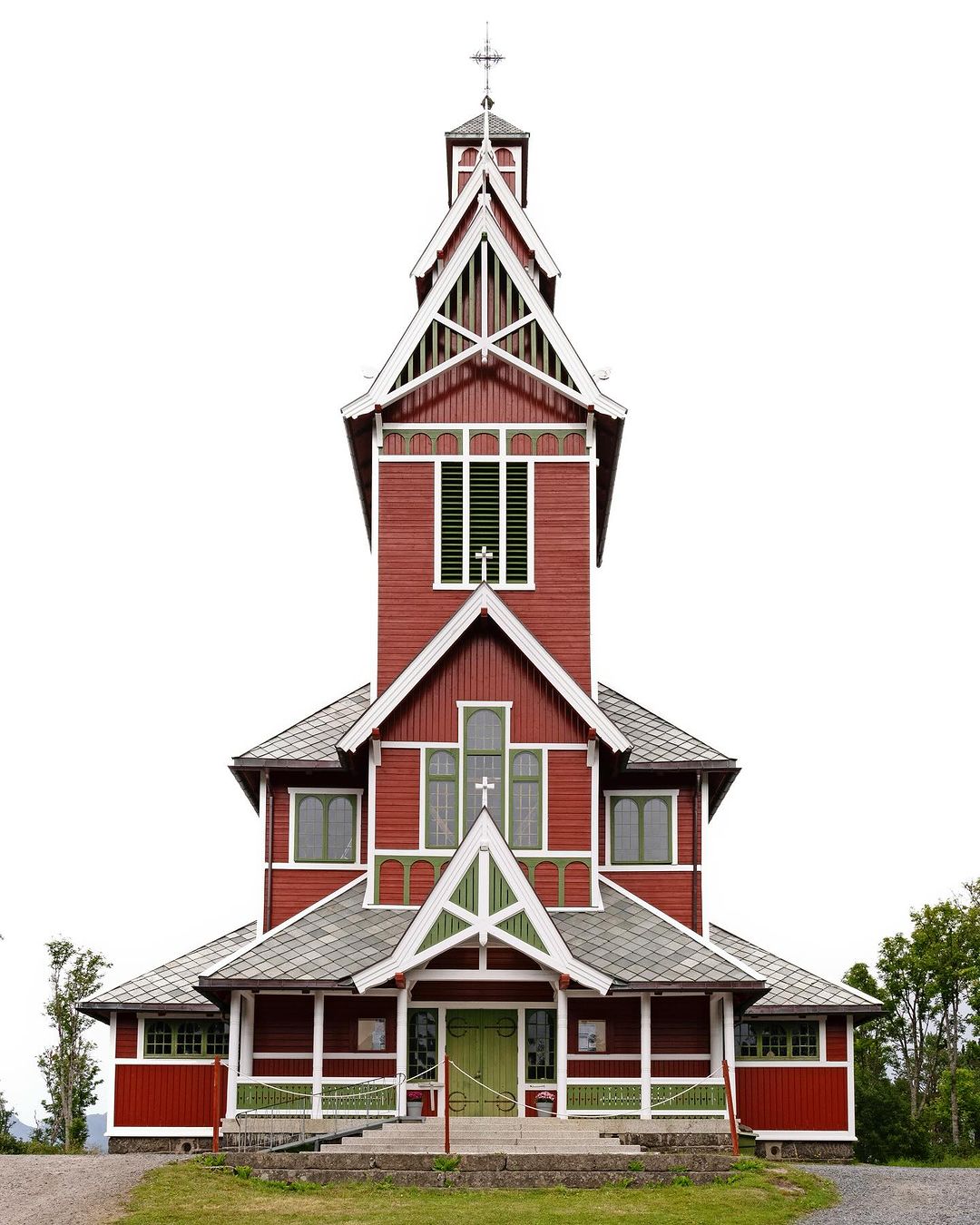 Exterior view of a traditional red wooden church with white trim and a tall steeple against a bright white sky. The architecture is intricate.