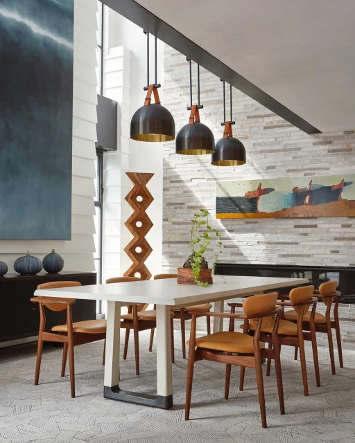Modern dining room featuring a white table surrounded by wooden chairs, pendant lighting, and decorative elements. Interior design.