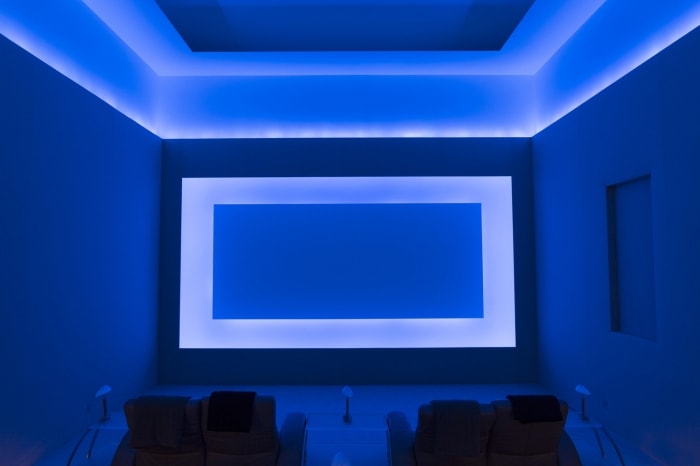 Modern blue-lit home theater featuring comfortable recliner chairs, large screen, and ambient lighting for an immersive viewing experience.