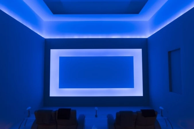 Modern blue-lit home theater featuring comfortable recliner chairs, large screen, and ambient lighting for an immersive viewing experience.