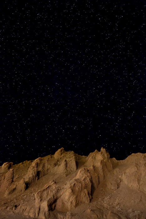Dramatic landscape of rocky mountains at night under a star-filled sky, highlighting natural beauty and tranquil scene.