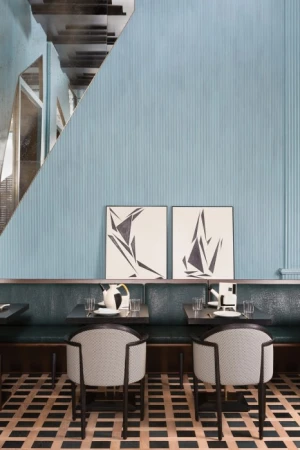 Restaurant interior features seating with chairs and banquette, abstract art, and patterned flooring in a contemporary design setting.